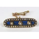 A seed pearl encrusted brooch of elongated oval form with three collet set pearls to a blue