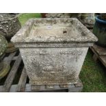 A large weathered composition stone planter of square form with classical urn and further relief