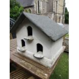A cream painted wooden framed dovecote with pitched felt roof and three arched entrances