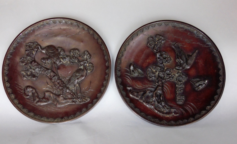 A pair of Japanese bronze chargers decorated in high relief with birds amidst branches, 36cm