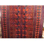 A Balochi rug principally in a red and blue colourway with multi star burst detail upon a divided