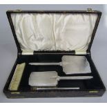 A cased art deco silver four piece dressing set comprising two brushes, a comb and a mirror, all