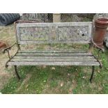 A two seat garden bench with weathered wooden slatted seat and back incorporating two rectangular