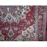 A Persian style wool rug with central medallion upon a white and ruby red field within alternating