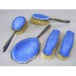 A 1920s five piece silver and guilloche enamel dressing set comprising four various brushes and a