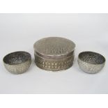 A pair of eastern white metal bowls embossed with Buddistic Deities amidst scrolled foliage, 11cm