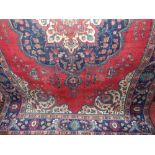 A good quality Persian carpet decorated with various blue and white floral medallions upon a red