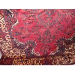 A good quality Persian carpet decorated with foliage upon a rich red ground, 320 x 210cm