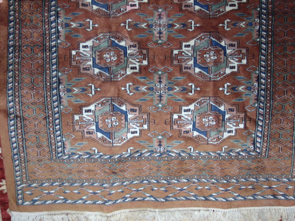 An Afghan style wool rug with mid brown field, multi medallion detail, set within alternating