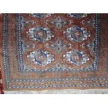 An Afghan style wool rug with mid brown field, multi medallion detail, set within alternating