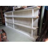 A substantial cream painted and pine framed floorstanding open bookcase with boarded back, fixed