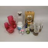 A mixed collection of glassware to include cranberry glass examples, glass paperweight, a decanter