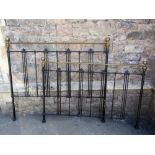 A Victorian style cast iron bed frame with brass finials and vertical rails to house a king size