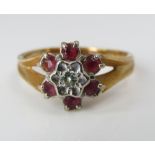 An 18ct flower head ring set with pink spinels and a central diamond, size N, 4g