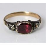 An early Georgian gold ring set with a central flat cut garnet flanked by two white stones, size Q/