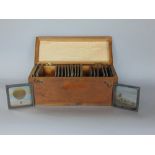 A wooden box fitted with a part collection of coloured glass magic lantern slides relating to