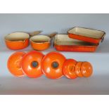 A collection of Le Crueset burnt orange cookware to include two saucepans, oven dishes, etc