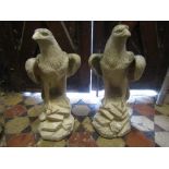 A pair of weathered reconstituted pillar ornaments in the form of eagles on rocky outcrops, 60cm