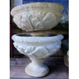 A pair of cast garden planters of circular form raised on waisted pedestals with repeating floral