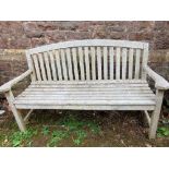 A weathered teak wood garden bench with stick back