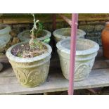 A weathered set of four cast garden planters, bucket shaped with repeating floral detail