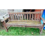 A weathered teak three seat garden bench with slatted seat and back