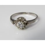 A diamond cluster ring in unmarked white metal, central diamond 0.30cts approx, size O/P, 3.4g