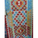 A flat weave Kelim runner with geometric colourway in red, blue and cream, 200 x 60cm approx