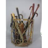 Early 20th century wrought iron bow shaped stick stand containing a collection of sticks and