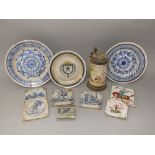 A collection of continental tin glazed earthenwares including a tankard with painted church