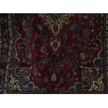 A heavy Persian wool carpet with central medallion upon a red ground, with scrolling floral