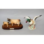 A Beswick model of a Jersey cow and calf raised on an oval wooden base, 24 cm long together with a