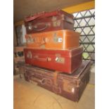 A stack of five vintage brown fibre and leather suit and other cases