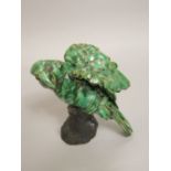 An unusual green glazed ceramic model of a parrot on a branch with incised initials to interior