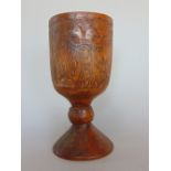 Early carved treen goblet decorated with panels of figures, a twin headed eagle and hunting scene on