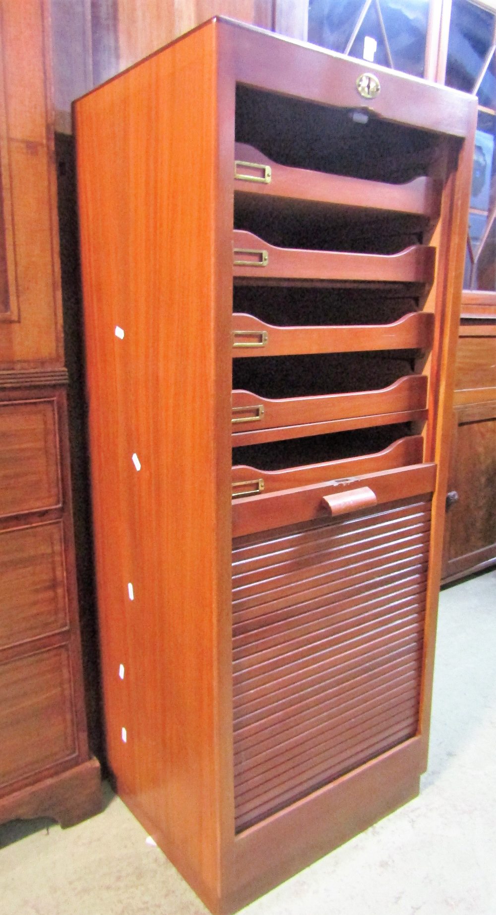 A teak floorstanding filing cabinet with rise and fall tambour door enclosing tray slides