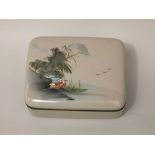 A Japanese cloisonné box and cover with mountain, bamboo, building and bird detail upon a steel grey