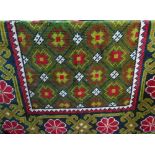 A deep pile wool rug in an eastern style, the unusual green ground field supporting a geometric