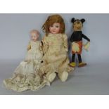 A vintage felt Mickey Mouse doll, 22cm high; together with a further bisque headed baby doll, with