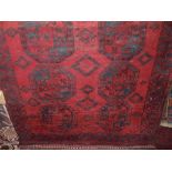 An Afghan red wool carpet with multi medallion centre upon a deep red field, within alternating