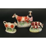 A 19th century Staffordshire cow creamer in the form of a milk maid and cow together with further