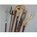 A mixed collection of canes to include walking staffs, a shooting stick, a tribal stick and