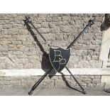 An ironwork shield shaped plaque initialled BP, mounted on an x frame with fleur-de-lys and open