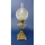 A Victorian oil lamp with pierced and cast iron base, wide fluted font and etched glass globe