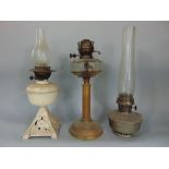 A late 19th century brass column oil lamp with clear glass font and two further examples, one with