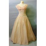 A 1950s ball gown in peach and ivory with fitted bodice, full skirt and a separate four hoop