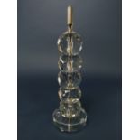 A heavy cut glass table lamp base with five repeating faceted spheres to the column and raised on