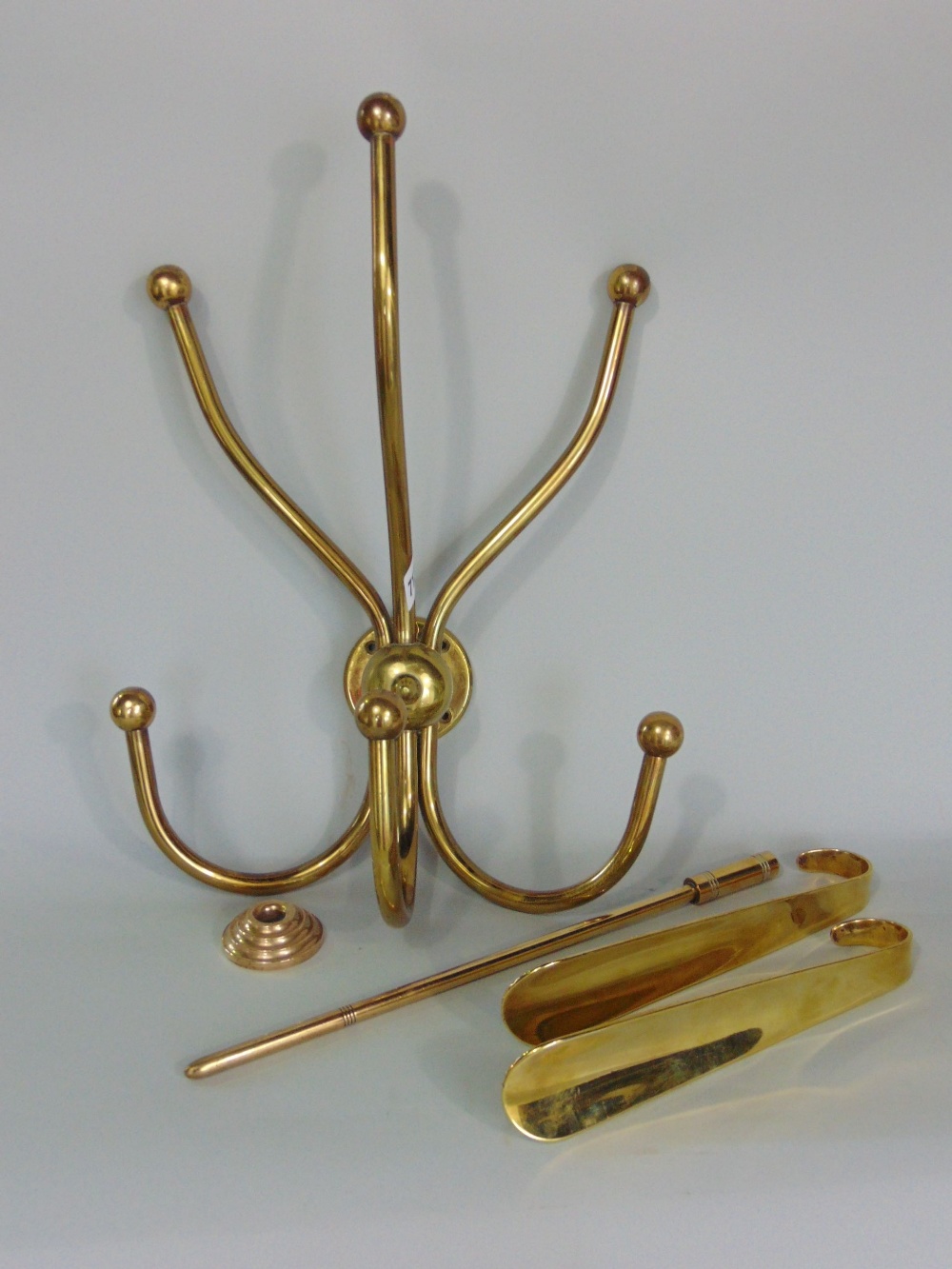 A mixed collection of brassware to include a three prong coat hook, two shoe horns and other