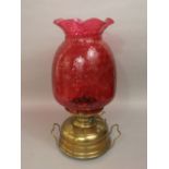 An early 20th century brass room heater with large cranberry glass pineapple shaped shade, shade
