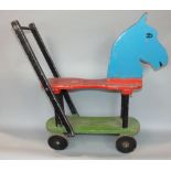 Carved wooden folk art toy horse, on four wheels with push handle, with painted finish, 60cm high